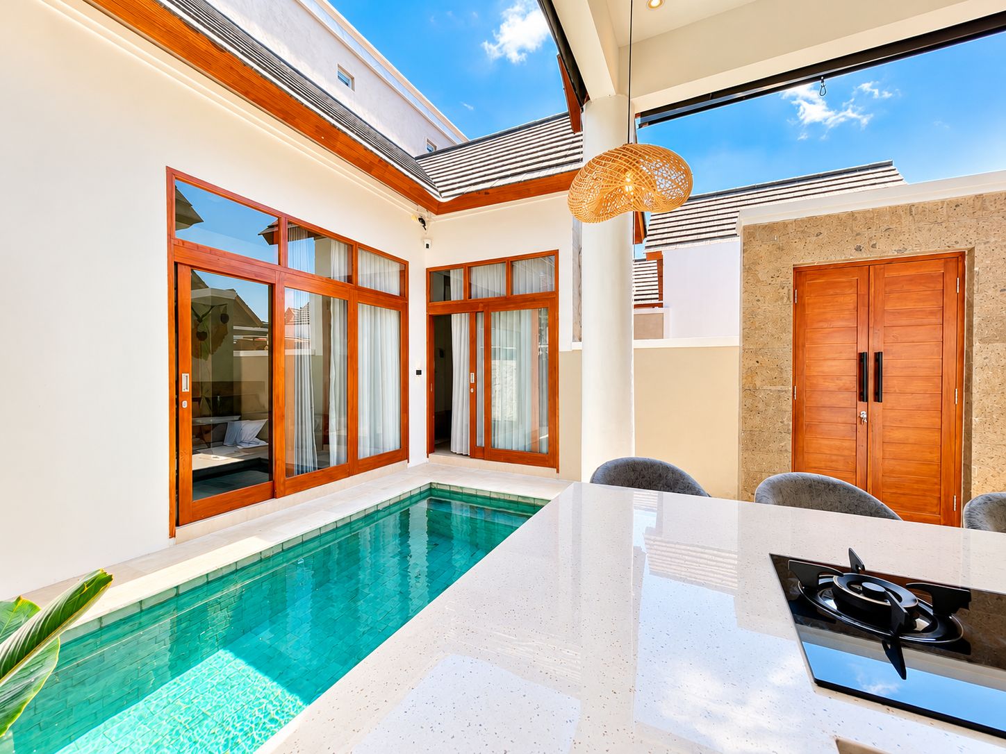 A modern pool area with glass doors, a dining table, and a stove.