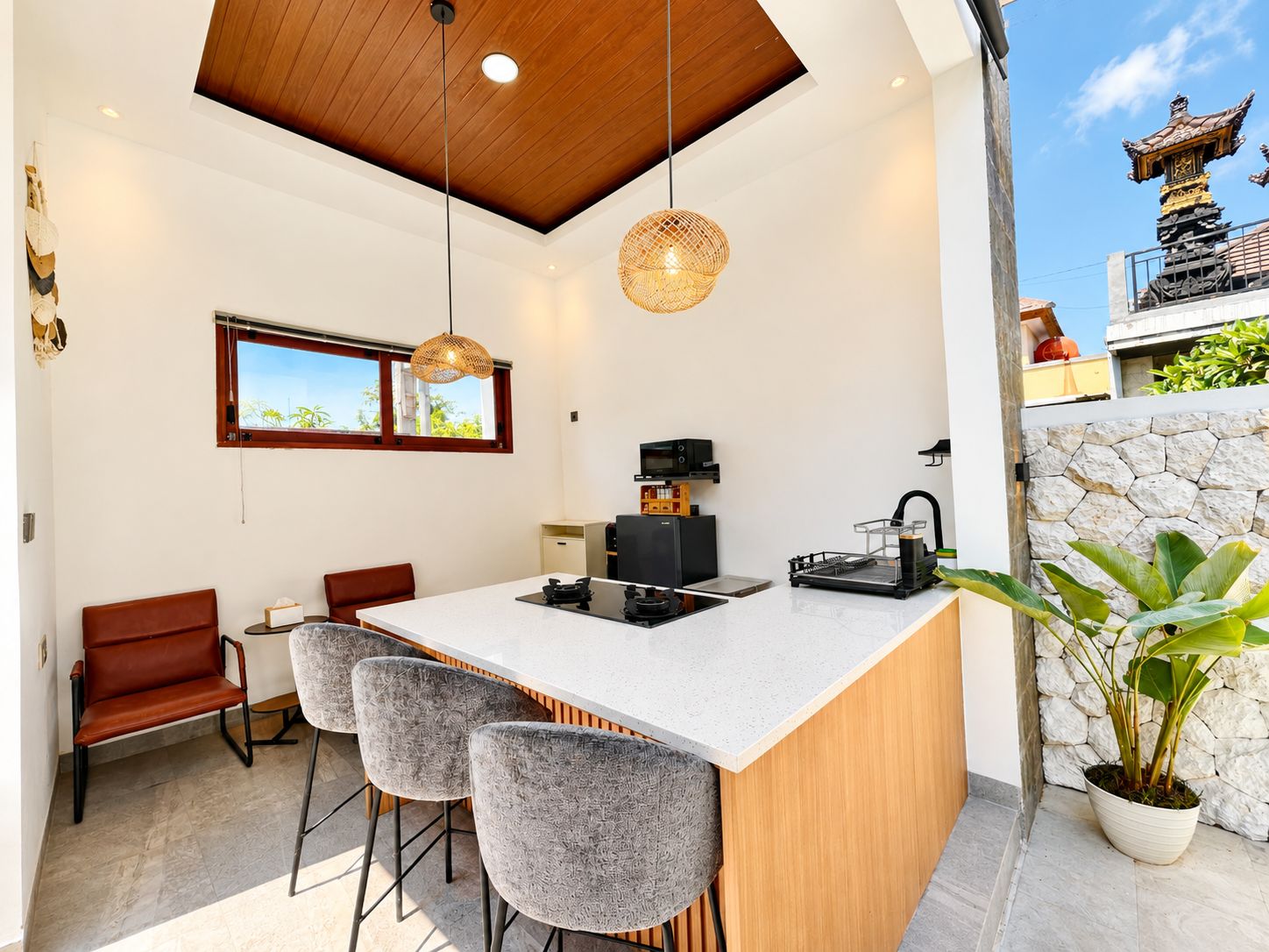 A modern kitchen with a central island, bar stools, a coffee machine, and a stone wall.