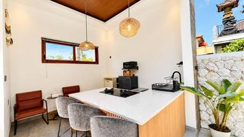 A modern kitchen with a central island, bar stools, a coffee machine, and a stone wall.