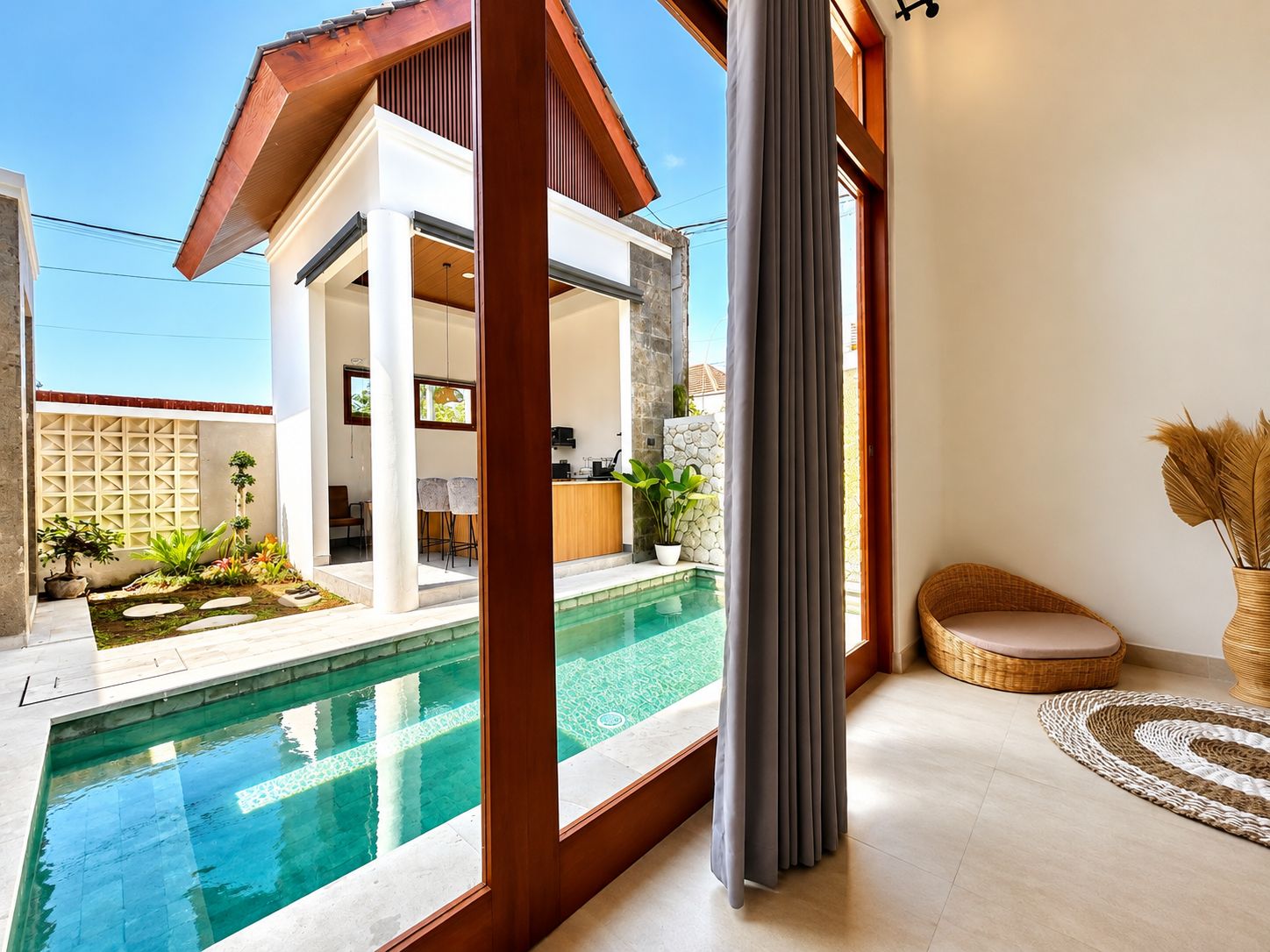 Une maison moderne dotée d’une piscine, d’un coin repas et d’un salon avec une grande fenêtre.
