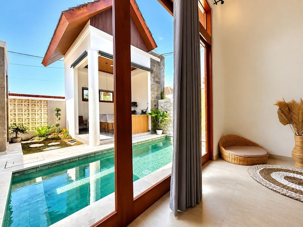 A modern house with a swimming pool, a dining area, and a living room with a large window.