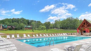 A swimming pool with lounge chairs and a wooden building in the background. - Awestruck: Hot Tub, Pool Access, Perfect Mountain Views, & Fireplace (Sevierville)