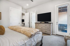 A bedroom with a bed, a dresser, a television, and a sliding door leading to a balcony. - Snow Canyon Oasis #66: Private Hot Tub (Santa Clara)