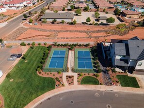 An aerial view of a residential area with two tennis courts, a swimming pool, and a road. - Snow Canyon Oasis #66: Private Hot Tub (Santa Clara)
