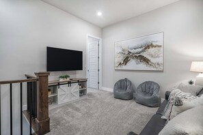 A living room with a flat-screen TV, a painting, and two bean bags. - Snow Canyon Poolhouse #65 + #66 (Santa Clara)