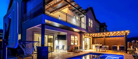 A two-story house with a swimming pool, outdoor seating, and a covered patio area.