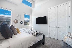 Ein Schlafzimmer mit Bett, Fernseher, Tür und Fenster.