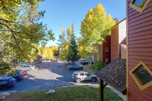 A parking lot with multiple cars, a building with a red exterior, and trees with yellow leaves. - Perfect Central Location - Walk to Base 9 Lifts (Breckenridge)