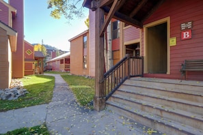 A building with a wooden staircase leading to a porch, a bench, and a sign indicating parking. - Perfect Central Location - Walk to Base 9 Lifts (Breckenridge)
