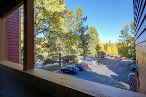 A view from a window overlooking a parking lot with several cars, trees, and a small building. - Perfect Central Location - Walk to Base 9 Lifts (Breckenridge)