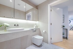 Ein modernes Badezimmer mit einem großen Spiegel, einem Waschbecken, einer Toilette und einer Duschkabine.