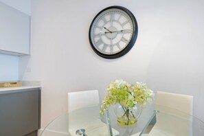 Ein moderner Essbereich mit einem runden Tisch, Stühlen und einer an der Wand hängenden Uhr.
