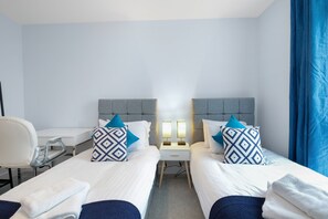 Ein Hotelzimmer mit zwei Betten, einem Schreibtisch und einem Stuhl.