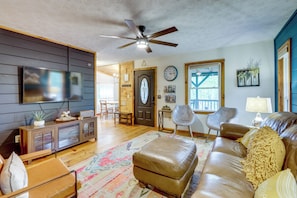 A living room with a leather sofa, a television, and a ceiling fan. - Cabin w/ Hot Tub, Near Mercier Orchard & Downtown (Blue Ridge)