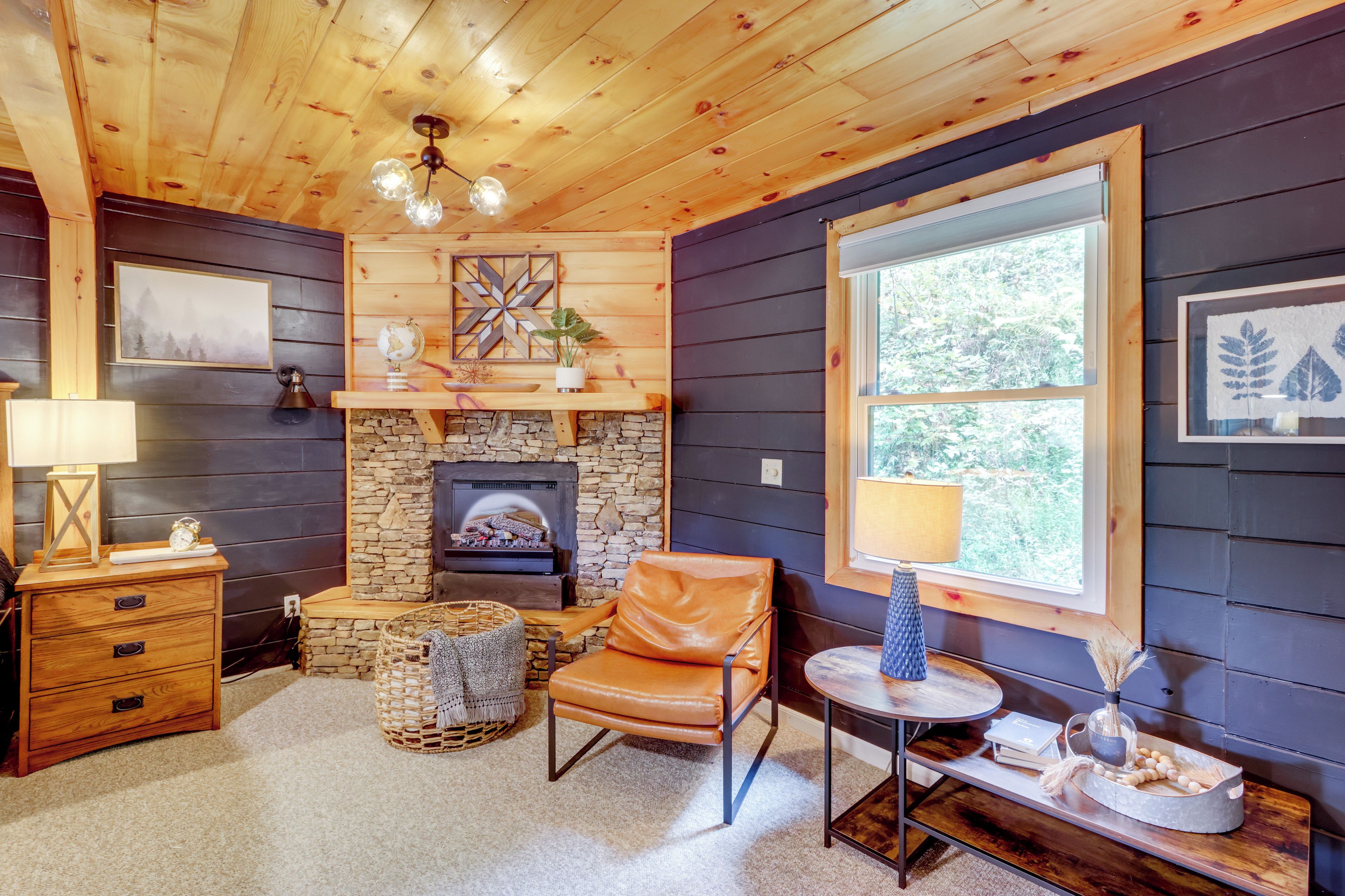 A cozy room with a stone fireplace, leather chair, and a large window.
