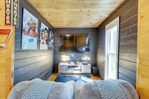 A cozy room with a wooden ceiling, a large window, and a flat-screen TV mounted on the wall. - Cabin w/ Hot Tub, Near Mercier Orchard & Downtown (Blue Ridge)