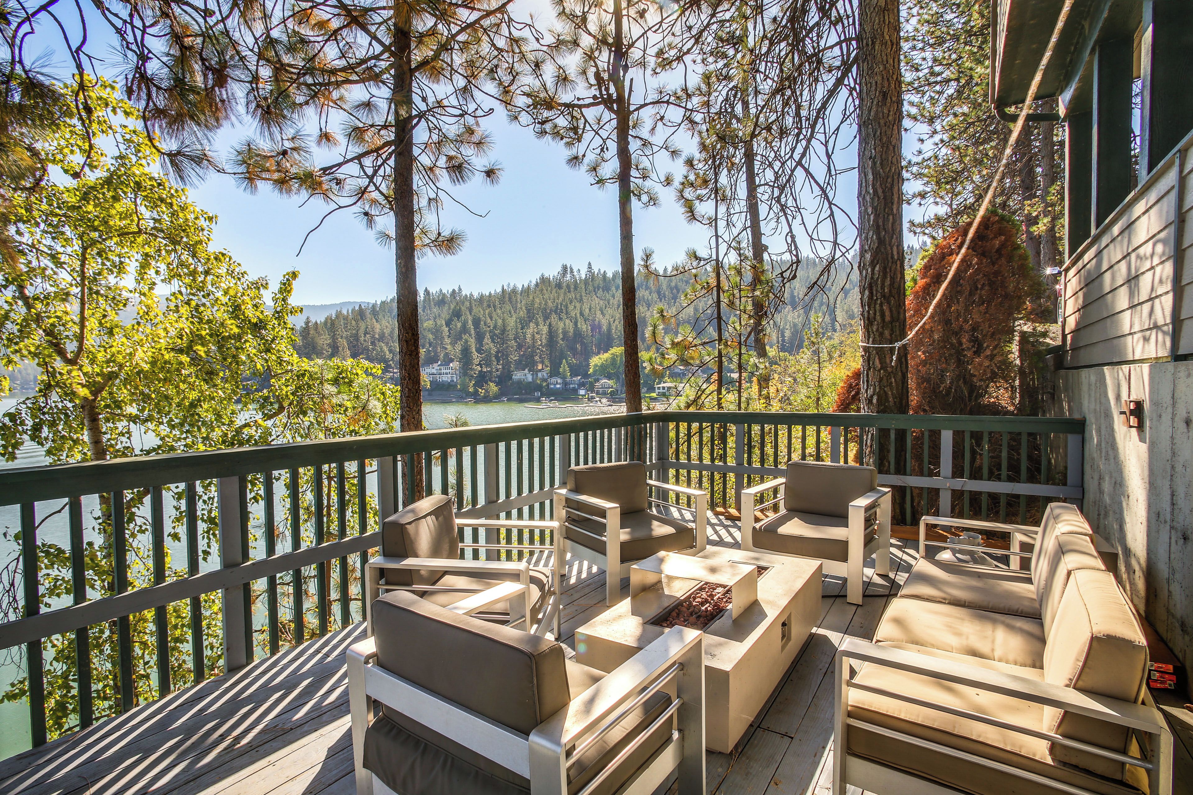 A deck with outdoor furniture overlooking a lake and forest.