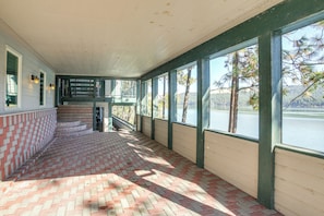 A covered walkway with a brick floor, wooden railings, and large windows overlooking a body of water. - Dock Access, Deck & BBQ on Liberty Lake (Liberty Lake)