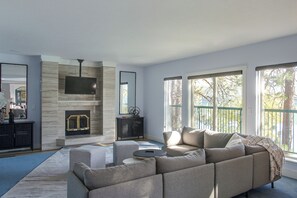 A modern living room with a fireplace, large windows, and a sectional sofa. - Liberty Lake Retreat w/ Private Dock (Liberty Lake)