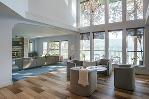 A spacious living area with a high ceiling, large windows, and a modern chandelier. - Liberty Lake Retreat w/ Private Dock (Liberty Lake)