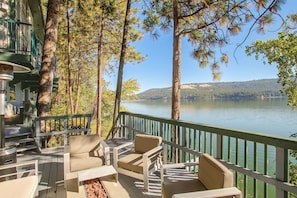 A deck with outdoor furniture overlooking a lake, surrounded by tall trees. - Liberty Lake Retreat w/ Private Dock (Liberty Lake)