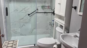 Une salle de bain moderne avec une douche en verre, des toilettes, un lavabo et un petit marchepied.