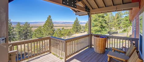 A wooden deck with a view of mountains and trees.