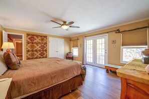 Ein Schlafzimmer mit Bett, Deckenventilator, Tür und Fenster mit Jalousien.