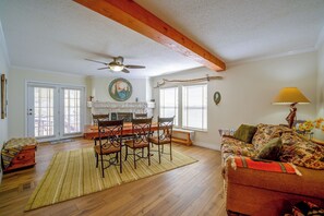 Ein geräumiges Wohnzimmer mit Holzboden, einer Essecke mit Tisch und Stühlen, einem Kamin und einem Sofa mit gemustertem Überwurf.