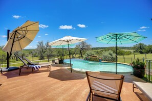 A swimming pool with lounge chairs and umbrellas, surrounded by a fence and greenery. - Fredericksburg House & Cabin 10 Mi to Main St (Fredericksburg)