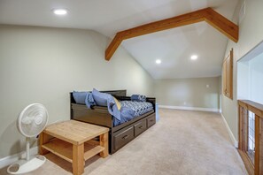 A bedroom with a bed, a fan, a wooden bench, and a sloped ceiling with wooden beams. - Fredericksburg House & Cabin 10 Mi to Main St (Fredericksburg)
