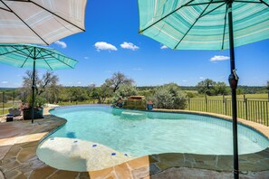 A swimming pool with stone tiles, surrounded by umbrellas, and a view of trees and hills in the background. - Fredericksburg House & Cabin 10 Mi to Main St (Fredericksburg)