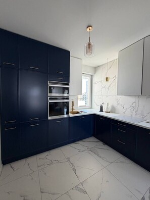 A modern kitchen with dark cabinetry, stainless steel appliances, and a marble backsplash. - Lumina 2room Apart near Old Town Balcony (Warszawa)