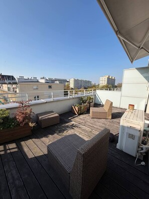 A rooftop terrace with wicker furniture, planters, and a view of city buildings. - Lumina 2room Apart near Old Town Balcony (Warszawa)