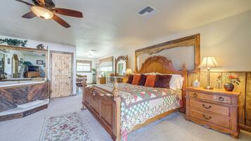 A bedroom with a wooden bed, a nightstand, a dresser, a ceiling fan, and a large mirror.