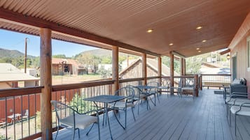 A covered outdoor patio with wooden flooring, metal chairs, and tables.