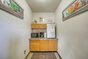 A compact kitchen with wooden cabinets, a microwave, a coffee maker, and a refrigerator. - Romantic Mtn-view Suite w/ Jacuzzi Tub in Pine (Pine)