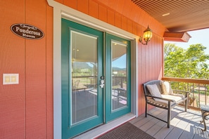 A wooden exterior with a teal door labeled 'Ponderosa Room' and a porch with a bench and a lantern. - Romantic Mtn-view Suite w/ Jacuzzi Tub in Pine (Pine)