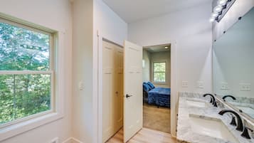 Un baño moderno con un espejo grande, dos lavamanos y una ducha.