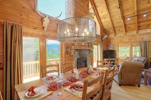 A wooden cabin interior with a dining area, a fireplace, and a television in the living room. - Mtn Views From Every Deck Without The Mtn Drive! (Maggie Valley)