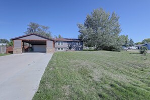 A residential property with a garage, a covered driveway, and a well-maintained lawn.