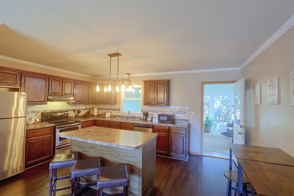 A modern kitchen with wooden cabinets, stainless steel appliances, and a central island with bar stools.
