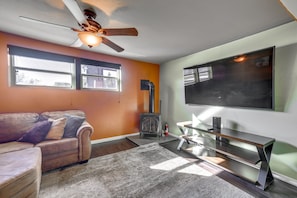 A living room with a sofa, a fireplace, a ceiling fan, and a TV mounted on the wall. - Private Hot Tub! Spacious Home in Rapid City (Rapid City)