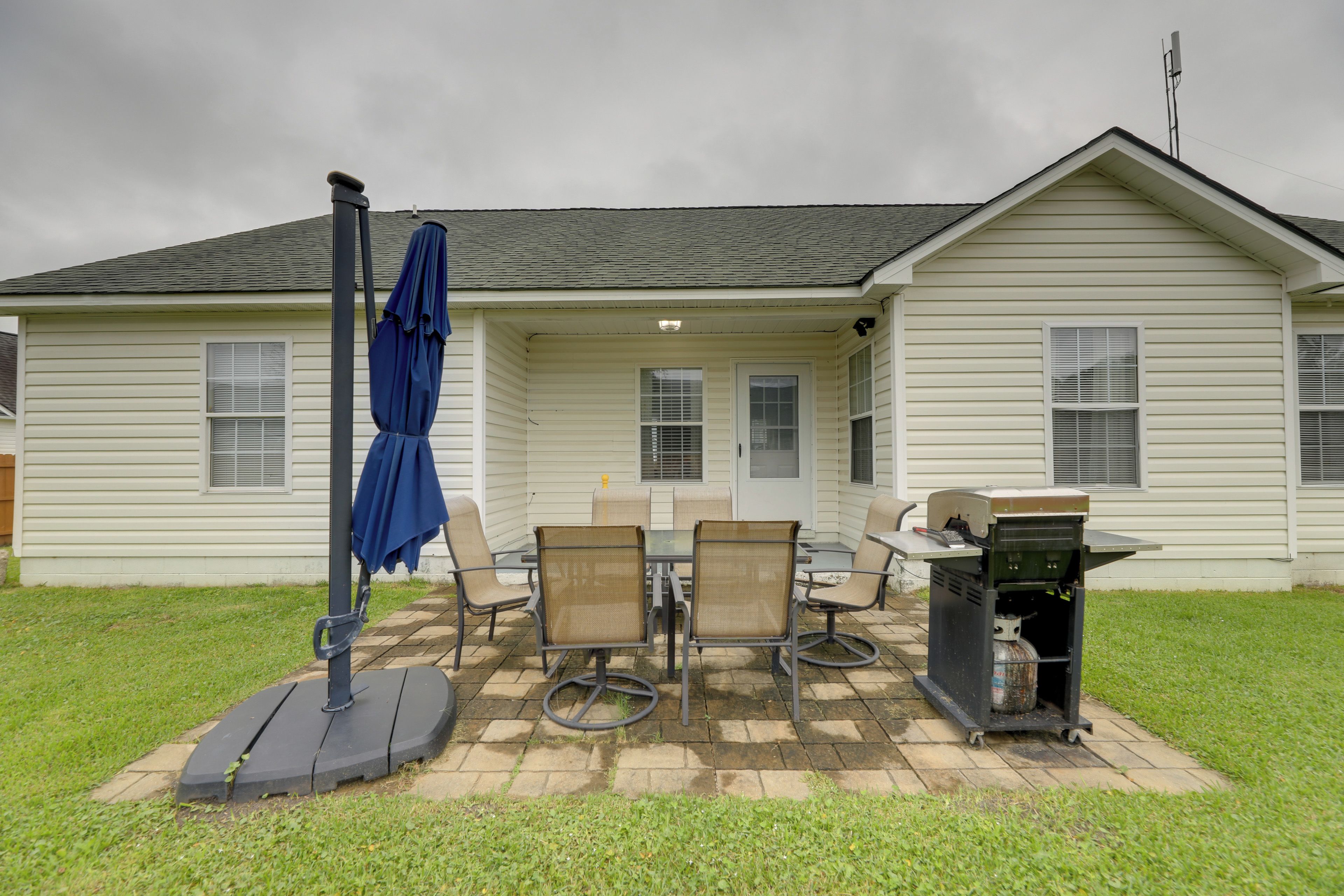 Une maison dotée d’un patio comprenant un barbecue, du mobilier d’extérieur et un parasol.