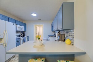 Una cocina moderna con armarios azules, encimera blanca y una isla central con un cuenco de flores.