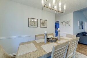 Un comedor con mesa de madera, sillas, una vela y un letrero de bienvenida.
