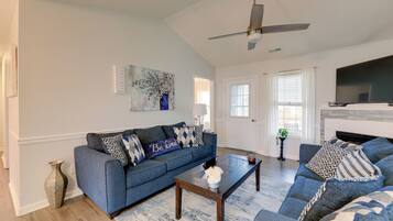 A living room with a blue sofa, a coffee table, a fireplace, and a television.