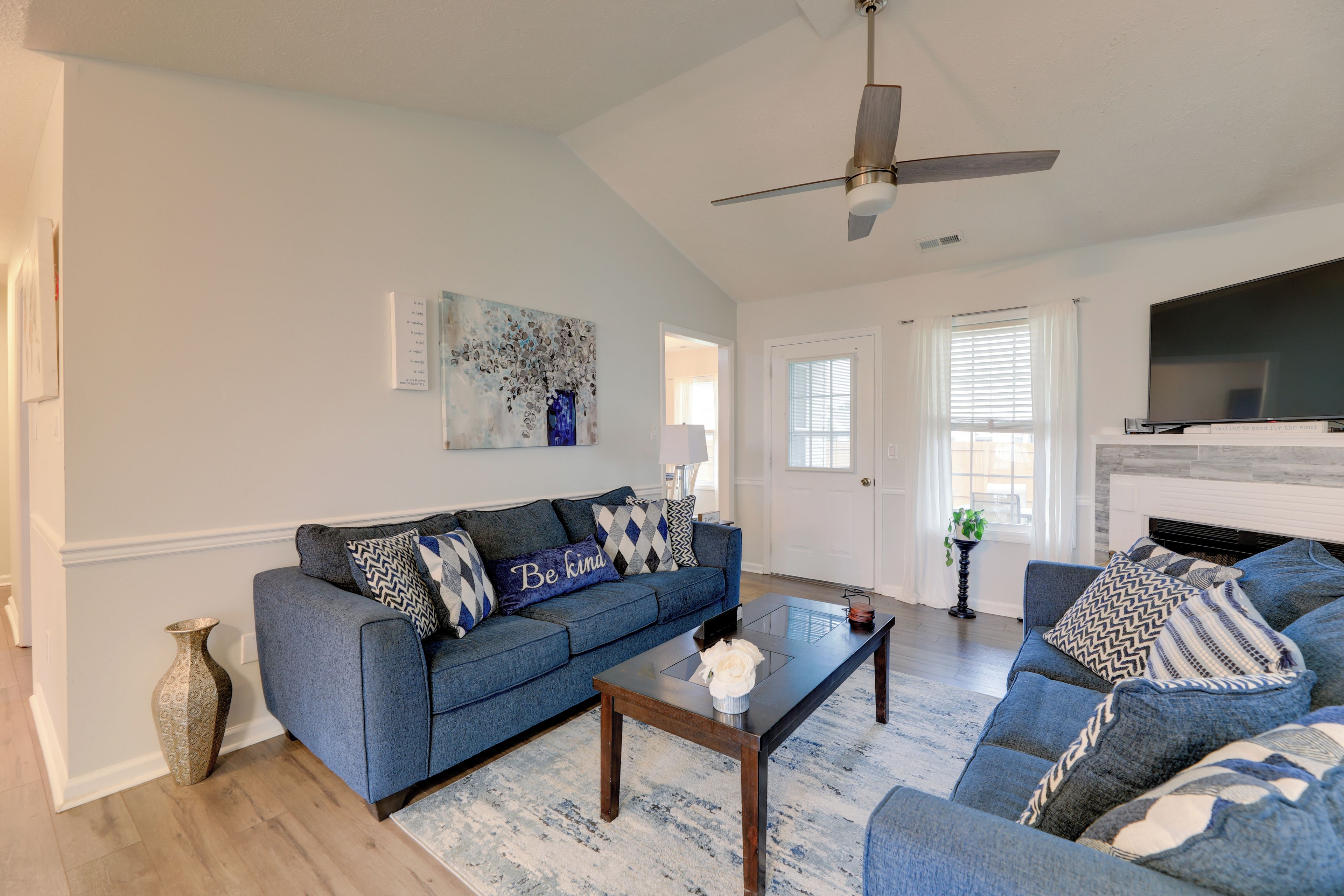 A living room with a blue sofa, a coffee table, a fireplace, and a television.