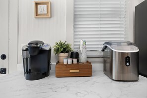 Una zona de cocina con cafetera, dispensador de agua y tetera sobre una encimera de mármol.