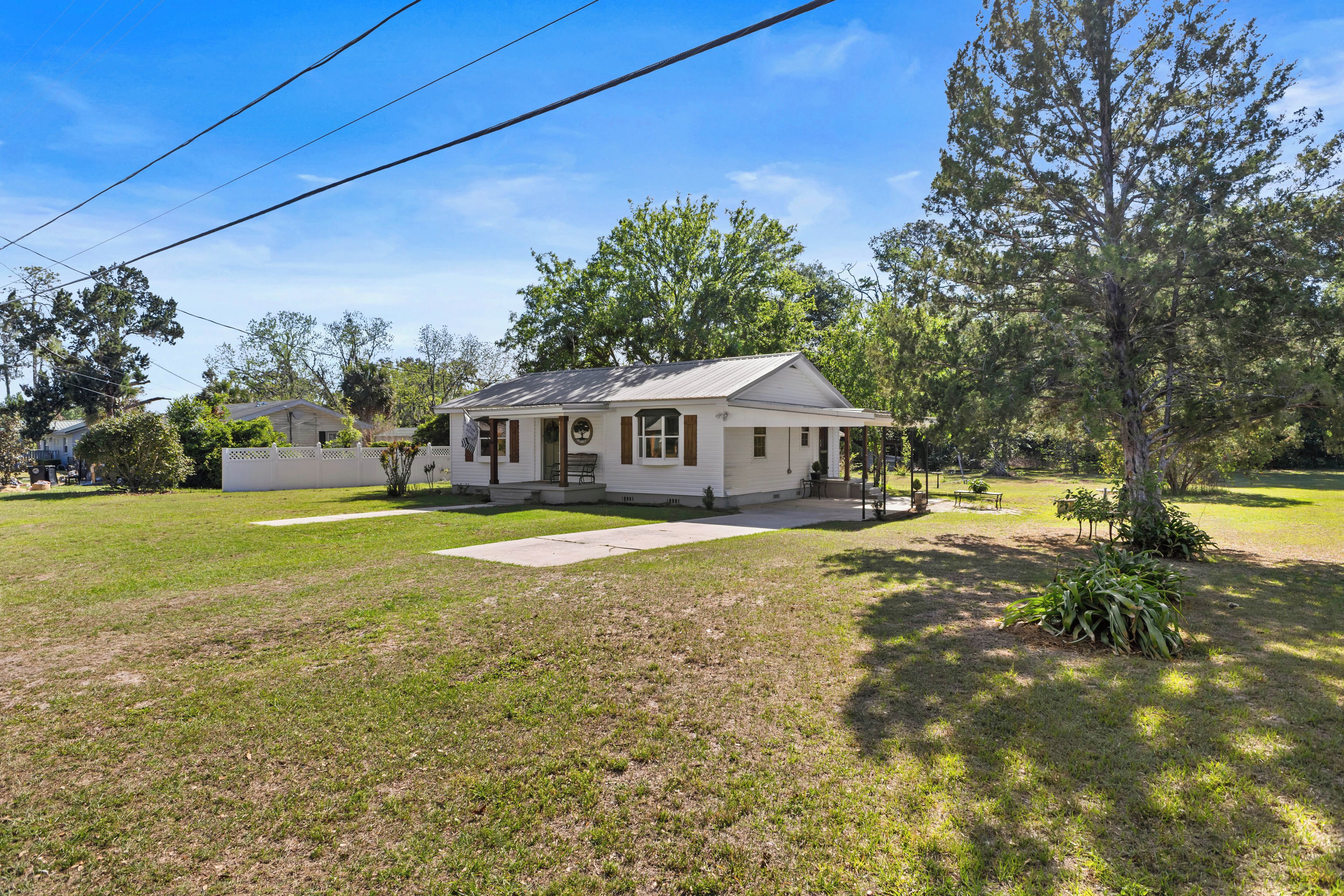 A single-story house with a front porch, a small yard, and a tree in front.